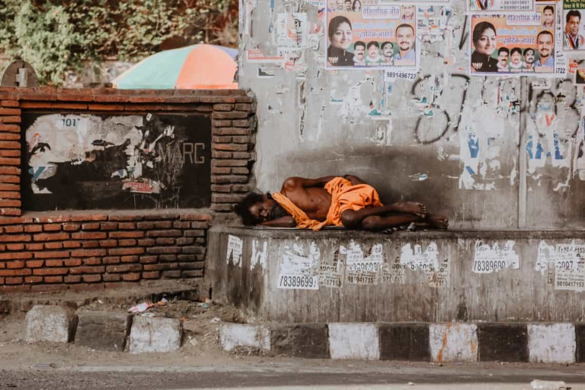 A poor homeless man sleeps by a temple india 2