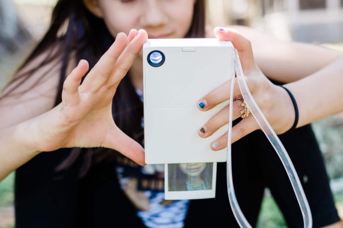 A polaroid mint camera printing a selfie of a young girl