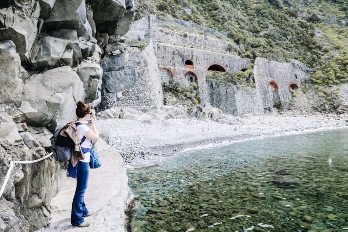 girl taking photos of beach cove italy 2
