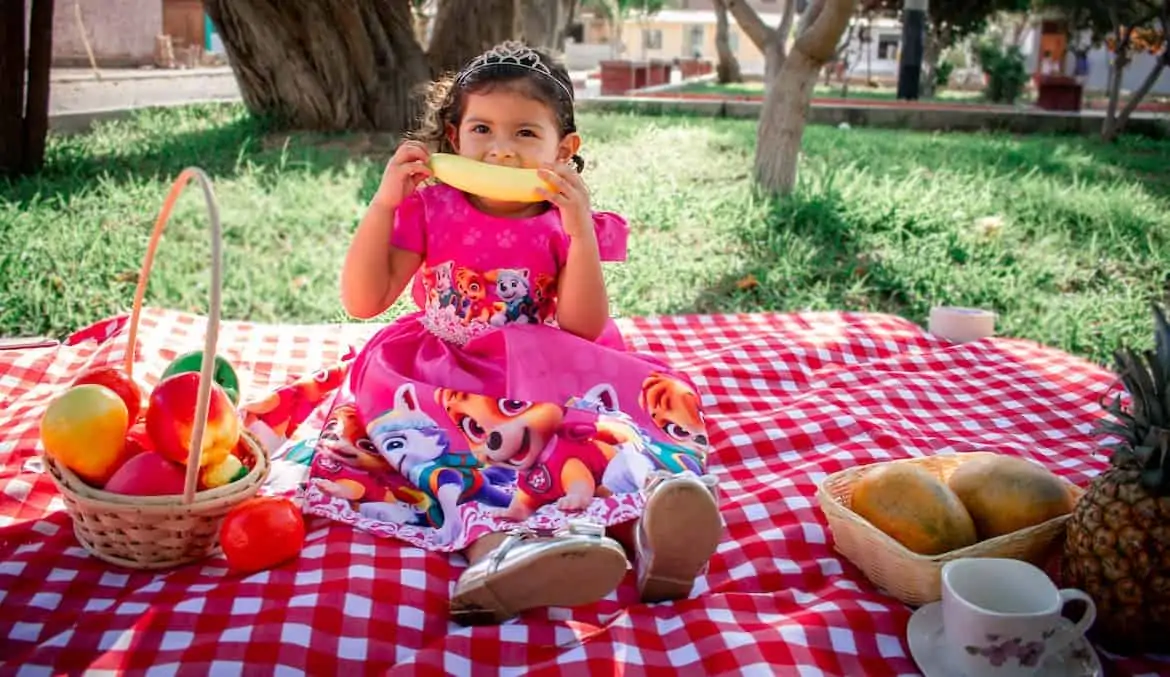 little girl enjoying picnic fruit snacks